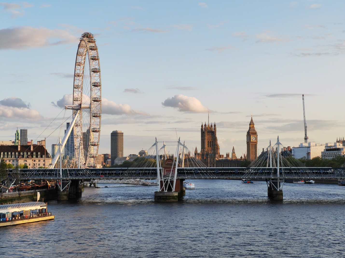 A bridge over a river with a ferris wheel

Description automatically generated