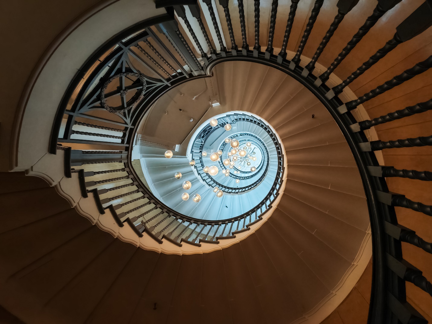 A spiral staircase with a chandelier

Description automatically generated