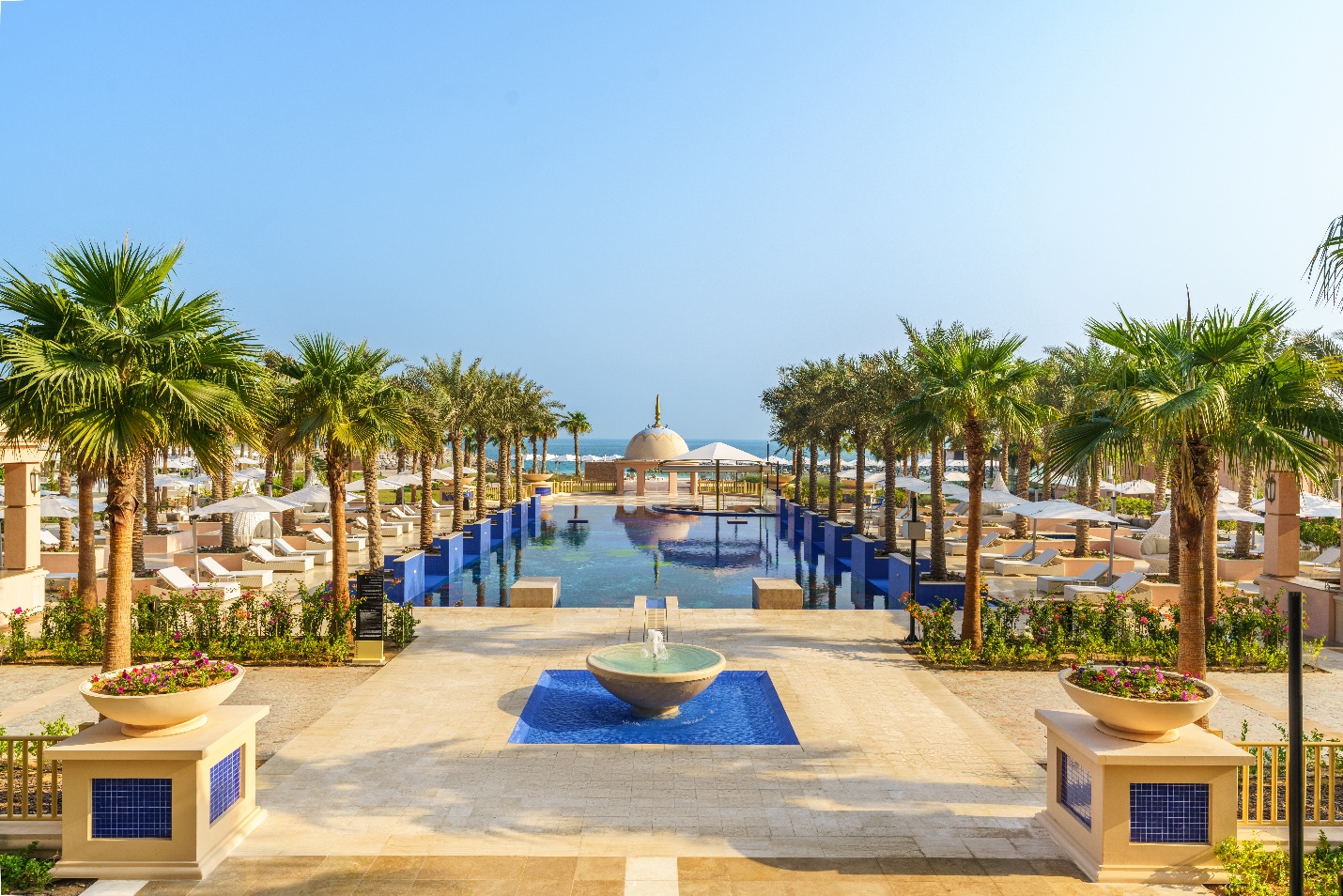 A pool with a fountain and palm trees

Description automatically generated